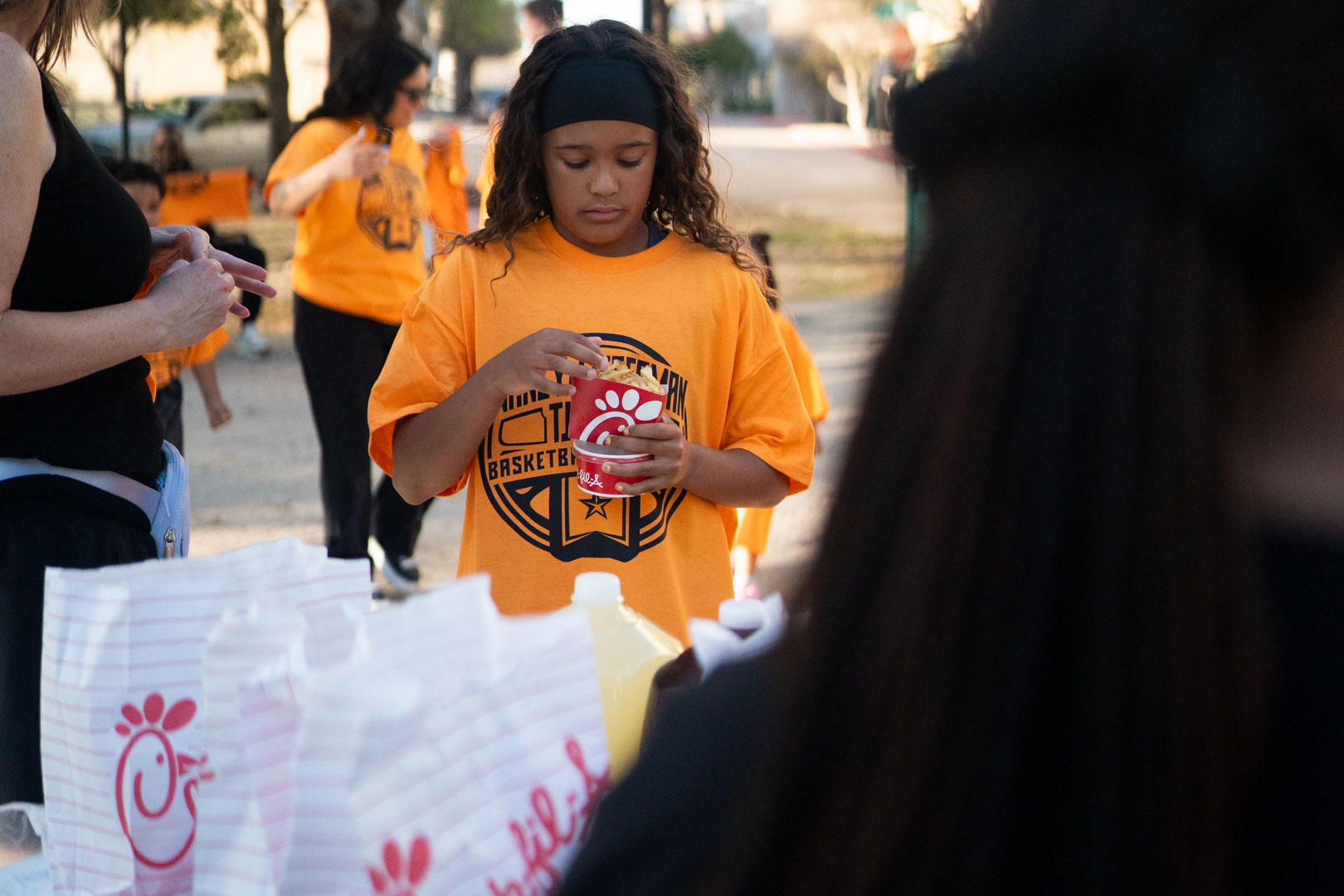 A girl in an Academy shirt eating Chick-fil-A fries at the pregame meal outside the arena