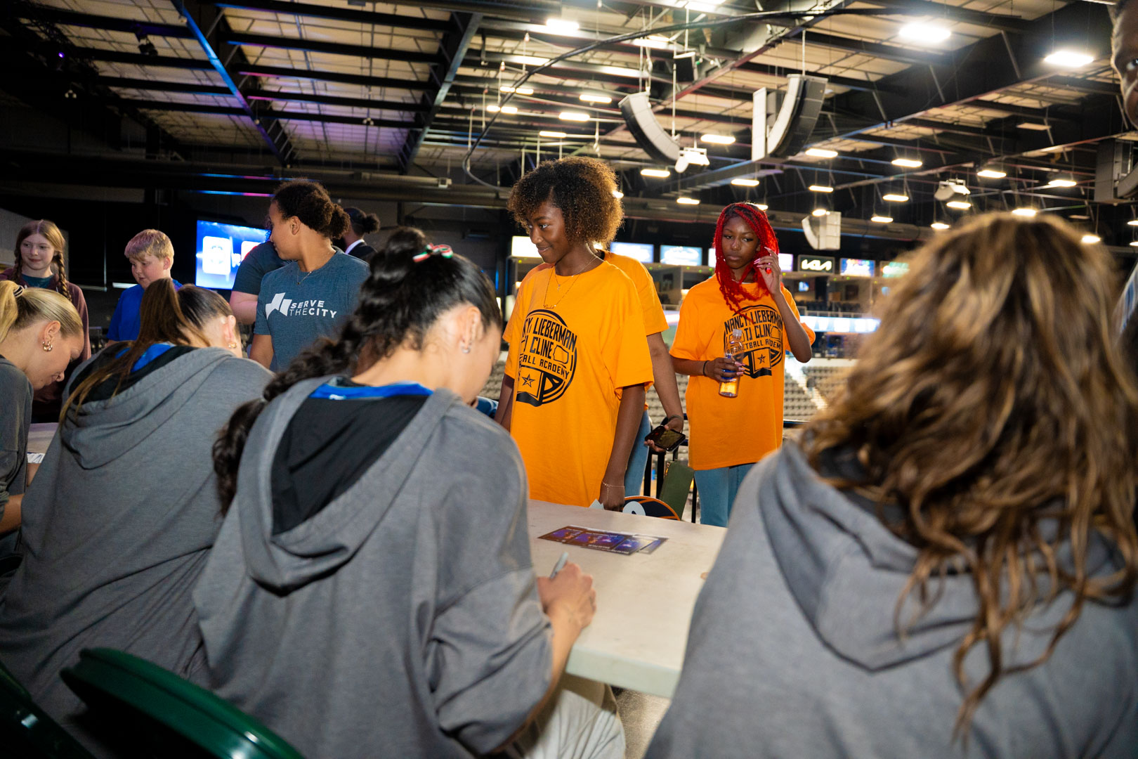 Two girls waiting at the autograph table while Dallas Pulse players sign cards