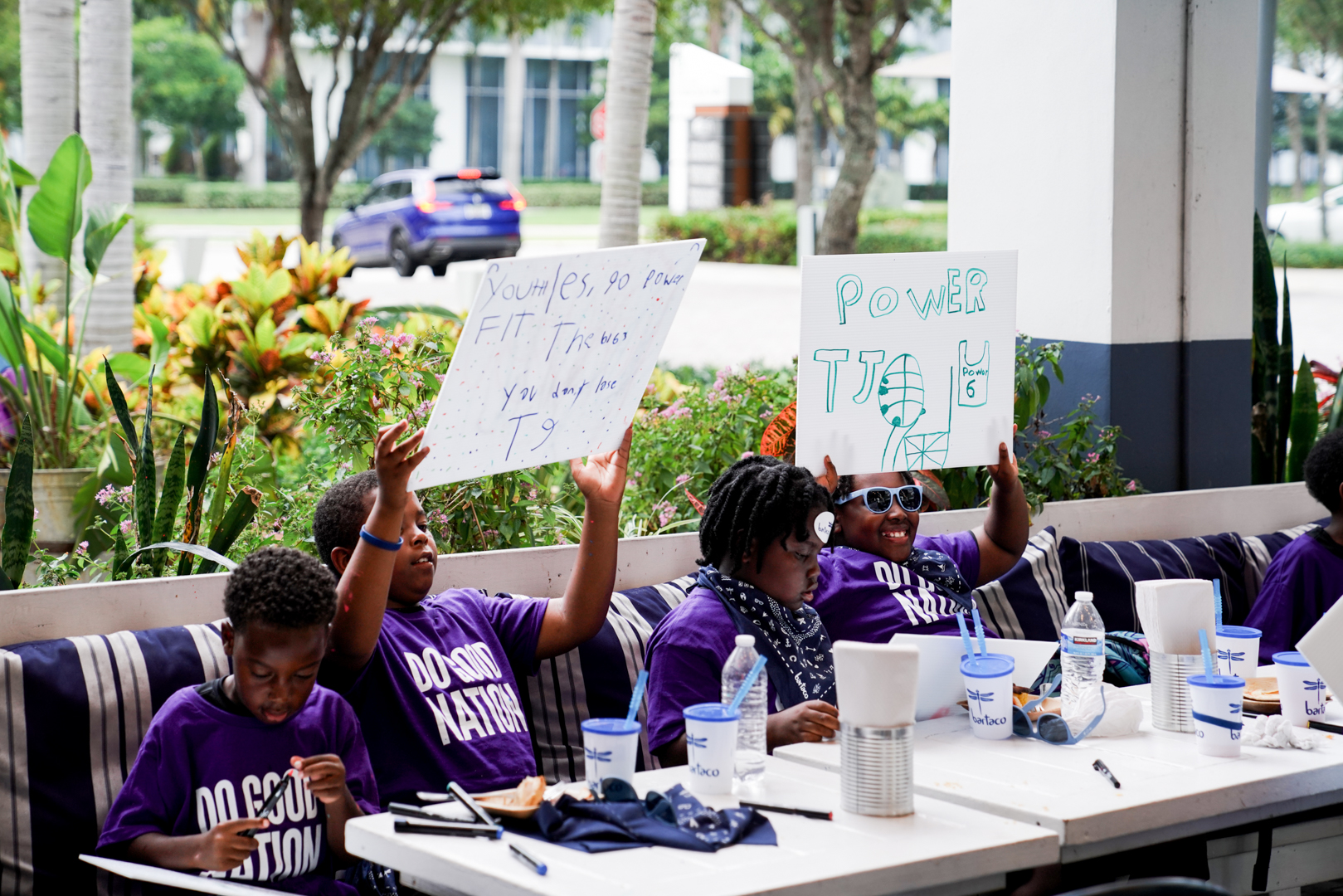 Kids holding up the game day signs they made at bartaco