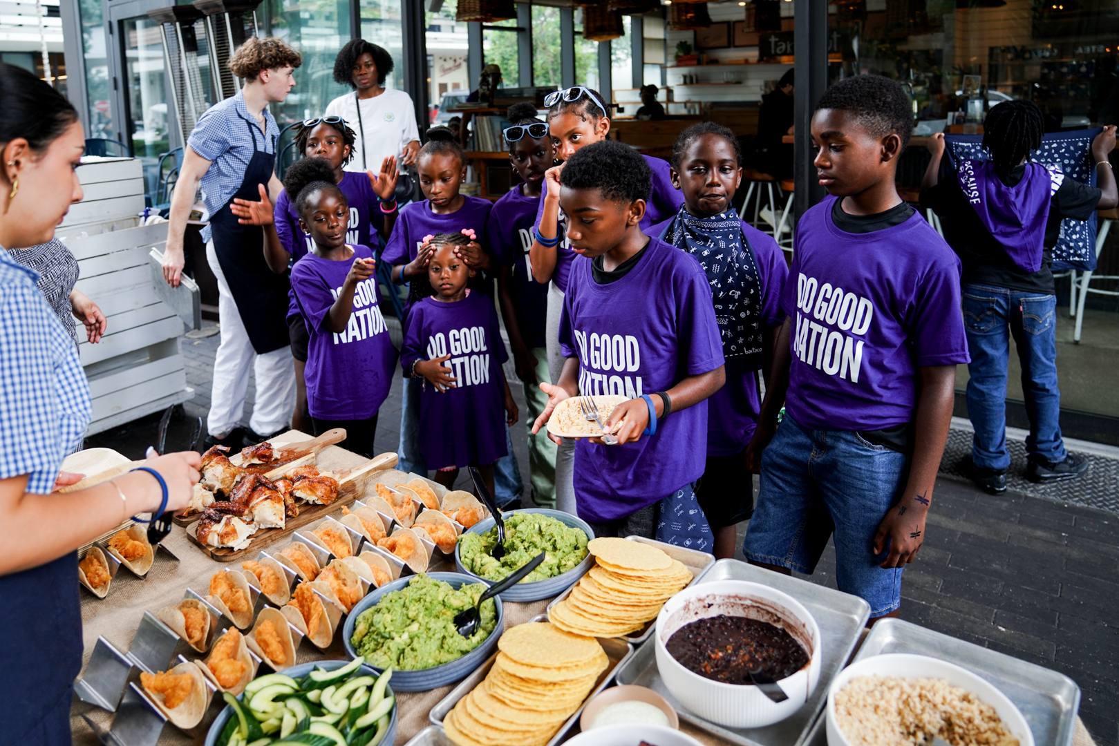 Youth in Do Good Nation shirts going through the food line at bartaco