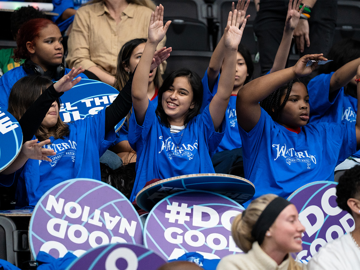 The Impact Section — youth with signs and fan gear cheering at a game